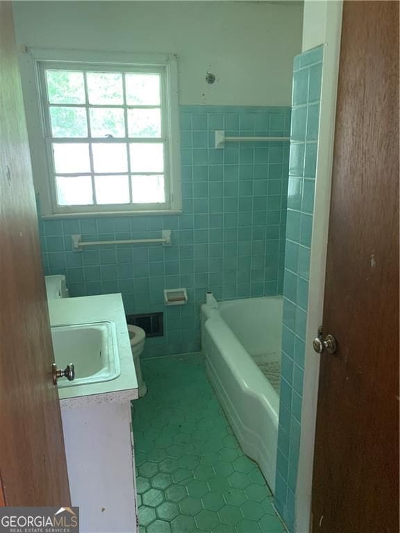 2703 Arrowood Dr, East Point, GA 30344 - bathroom with tile patterned flooring, vanity, tile walls, toilet, and a tub to relax in
