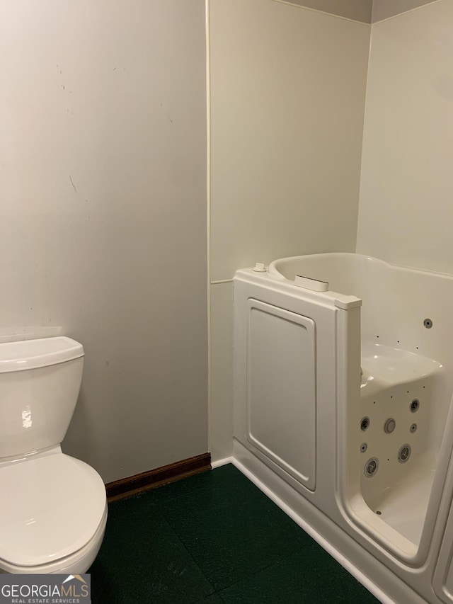 2242 Oakgrove Cir, Valdosta, GA 31602 - bathroom featuring toilet, a tub with jets, and baseboards