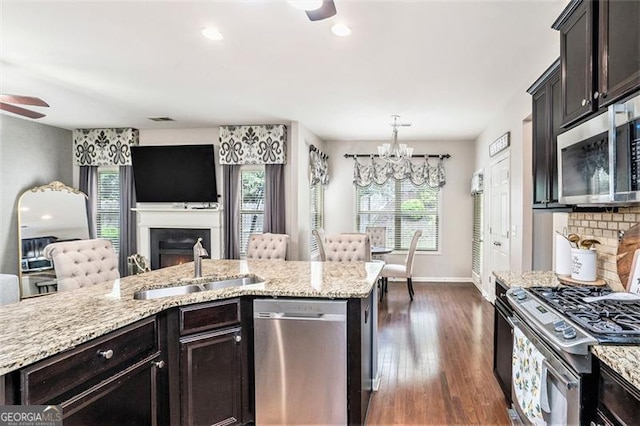230 Haleys Ct, Woodstock, GA 30188 - kitchen with stainless steel appliances, a sink, a chandelier, a warm lit fireplace, and light stone countertops