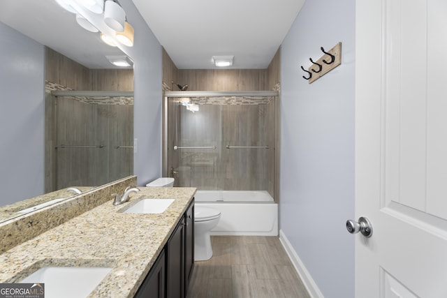 2067 Kinridge Ct, Marietta, GA 30062 - bathroom featuring toilet, double vanity, wood finished floors, combined bath / shower with glass door, and baseboards