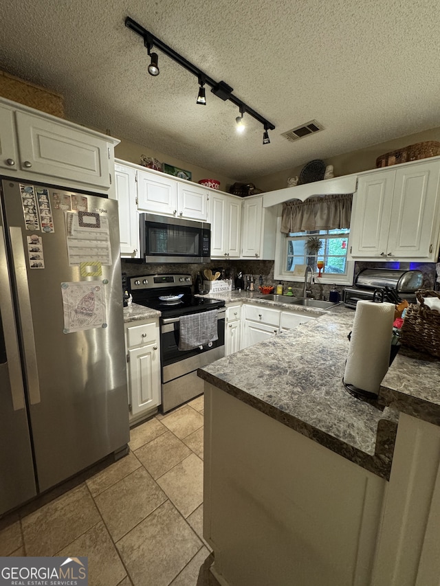 160 W Fork Dr, Newnan, GA 30263 - kitchen with stainless steel appliances, white cabinets, a sink, a textured ceiling, and decorative backsplash
