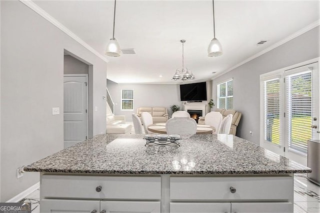 413 Huntleigh Shores Ln, Dallas, GA 30132 - kitchen featuring crown molding, a center island, light stone counters, a warm lit fireplace, and a chandelier