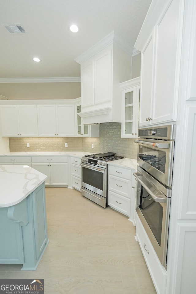 215 Jake Colton Dr, Kingsland, GA 31548 - kitchen with stainless steel appliances, ornamental molding, white cabinetry, glass insert cabinets, and recessed lighting