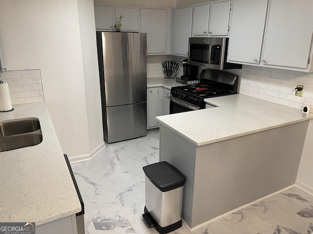 401 Bainbridge Dr, Mcdonough, GA 30253 - kitchen featuring light marble finish floors, stainless steel appliances, baseboards, a peninsula, and decorative backsplash