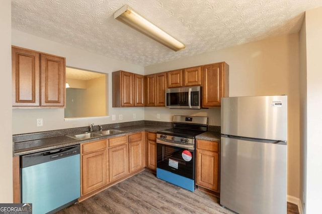 1851 Grove Way, Hampton, GA 30228 - kitchen with appliances with stainless steel finishes, dark countertops, light wood finished floors, a textured ceiling, and brown cabinetry