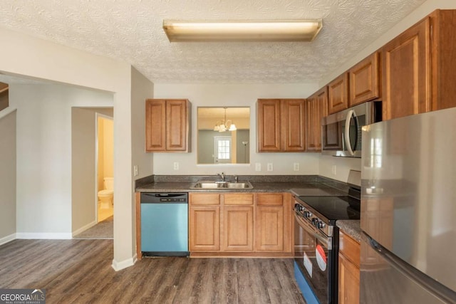 1851 Grove Way, Hampton, GA 30228 - kitchen with stainless steel appliances, dark countertops, dark wood finished floors, a textured ceiling, and brown cabinets