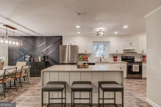 2020 Commonwealth Pl, Cumming, GA 30041 - kitchen featuring stainless steel appliances, a sink, a breakfast bar, crown molding, and under cabinet range hood