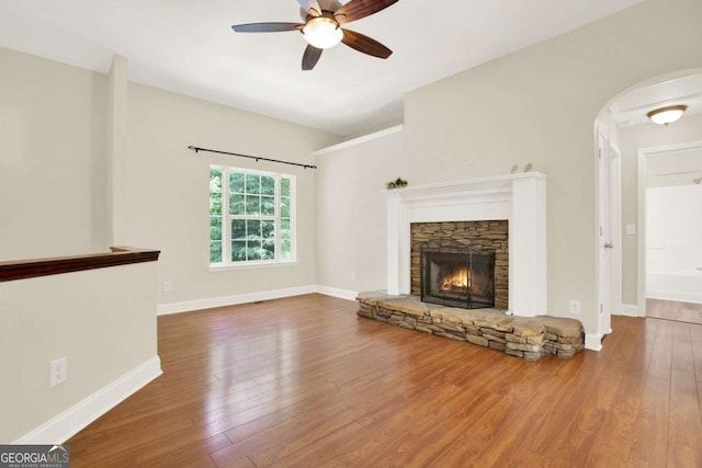 405 Scenic View Dr, Jasper, GA 30143 - unfurnished living room with ceiling fan, wood finished floors, a stone fireplace, and arched walkways