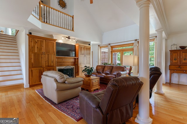 4320 Sandy Creek Rd, Madison, GA 30650 - living room with decorative columns, stairs, light wood-style floors, high vaulted ceiling, and a fireplace