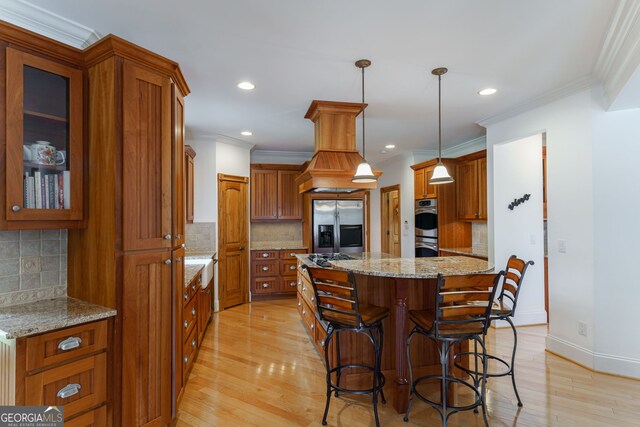 4320 Sandy Creek Rd, Madison, GA 30650 - kitchen with stainless steel appliances, brown cabinets, a kitchen island, ornamental molding, and a kitchen bar
