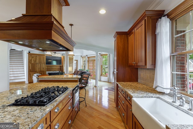4320 Sandy Creek Rd, Madison, GA 30650 - kitchen with a sink, black gas stovetop, open floor plan, brown cabinetry, and light wood-type flooring