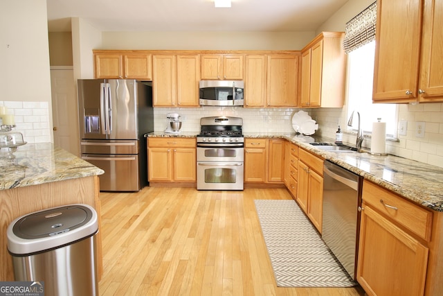 318 Ivy Manor Dr, Marietta, GA 30064 - kitchen with appliances with stainless steel finishes, a sink, backsplash, light wood finished floors, and light stone countertops