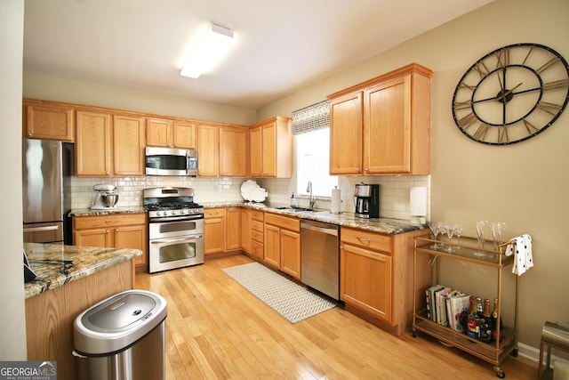 318 Ivy Manor Dr, Marietta, GA 30064 - kitchen featuring appliances with stainless steel finishes, light wood-type flooring, a sink, backsplash, and light stone counters