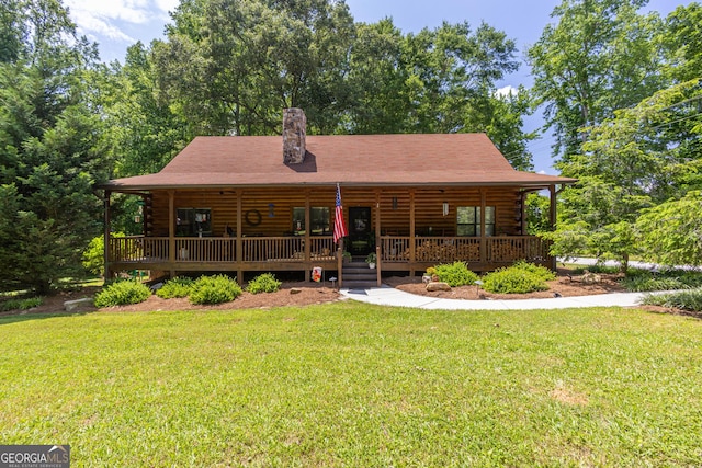 912 Folds Rd, Carrollton, GA 30116 - log-style house featuring log siding, a front yard, a chimney, and covered porch