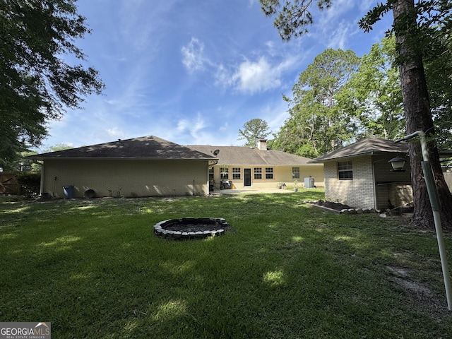 281 Cambridge Cir, Kingsland, GA 31548 - rear view of house featuring a patio area, a yard, brick siding, a chimney, and a fire pit