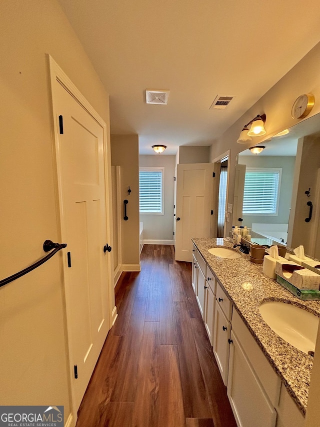 523 Huntleigh Dr, Winder, GA 30680 - full bathroom featuring double vanity, a garden tub, wood finished floors, and baseboards