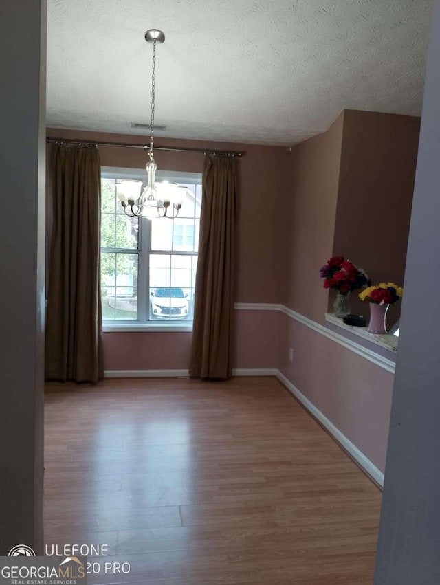 2918 Egret Ln, Austell, GA 30106 - unfurnished dining area with wood finished floors, a chandelier, baseboards, and a textured ceiling
