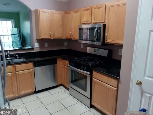 2918 Egret Ln, Austell, GA 30106 - kitchen featuring appliances with stainless steel finishes, light brown cabinetry, light tile patterned flooring, a sink, and arched walkways