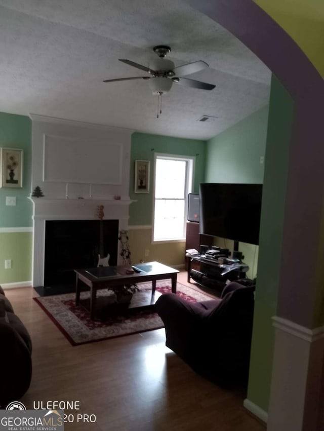 2918 Egret Ln, Austell, GA 30106 - living area featuring ceiling fan, a fireplace with flush hearth, wood finished floors, arched walkways, and a wainscoted wall