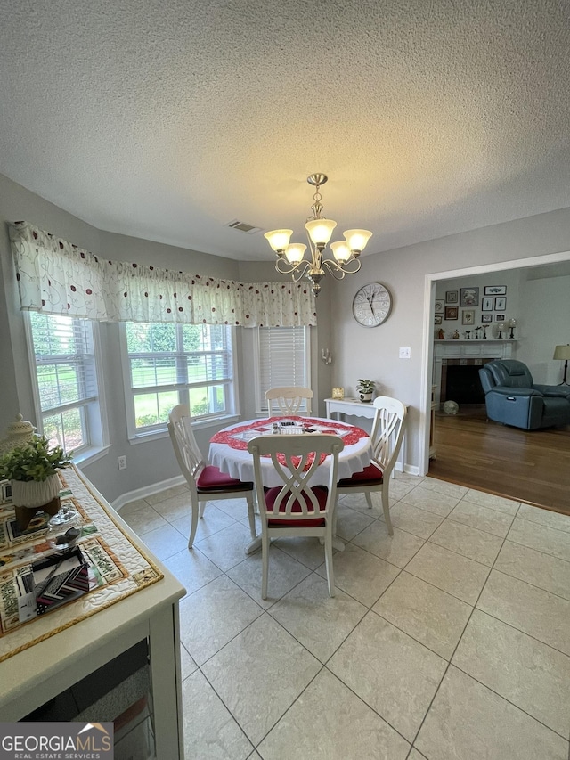 205 Ellicott Dr, Warner Robins, GA 31088 - dining area with a chandelier, light tile patterned flooring, a textured ceiling, baseboards, and a fireplace