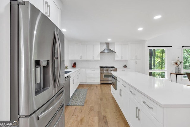 510 Watergate Ct, Roswell, GA 30076 - kitchen featuring appliances with stainless steel finishes, wall chimney range hood, a center island, light wood-type flooring, and light countertops