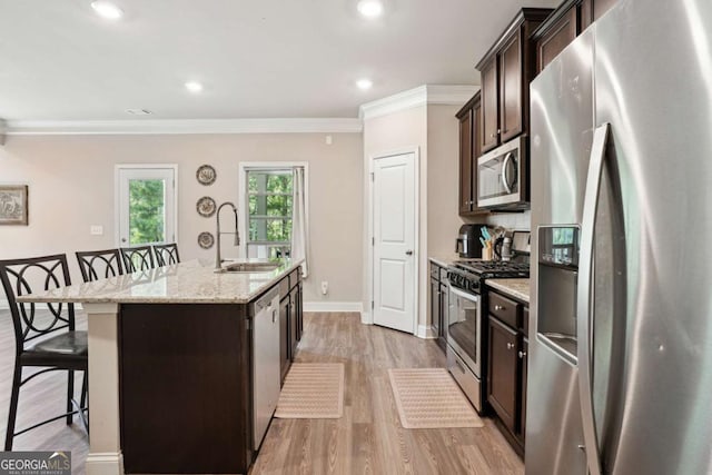 106 Logan Pass Dr, Loganville, GA 30052 - kitchen with appliances with stainless steel finishes, a sink, a kitchen bar, dark brown cabinets, and crown molding