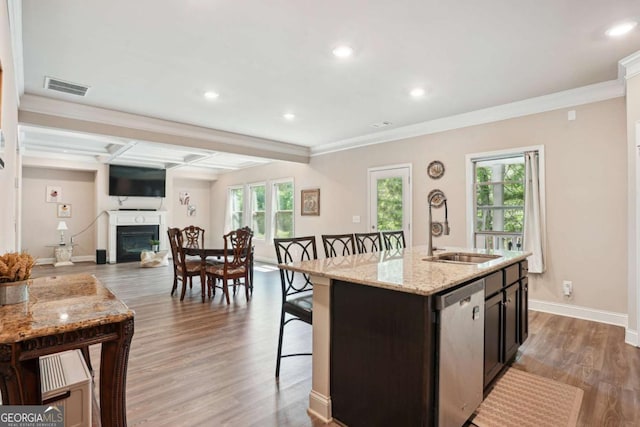 106 Logan Pass Dr, Loganville, GA 30052 - kitchen featuring stainless steel dishwasher, a sink, a glass covered fireplace, a kitchen bar, and an island with sink