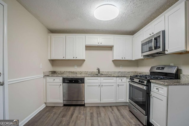 2290 Pope Rd, Douglasville, GA 30135 - kitchen with stainless steel appliances, wood finished floors, a textured ceiling, white cabinetry, and light stone counters