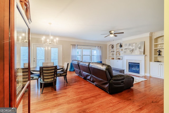 3623 Terrah Point Dr, Duluth, GA 30097 - living room featuring a chandelier, built in shelves, light wood-type flooring, ornamental molding, and a glass covered fireplace