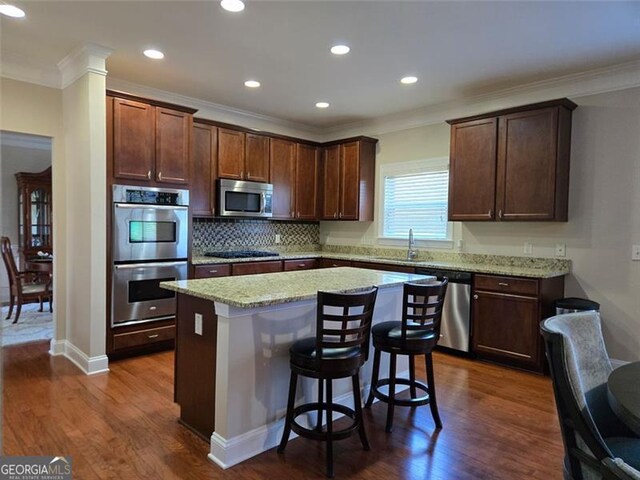 3623 Terrah Point Dr, Duluth, GA 30097 - kitchen with stainless steel appliances, a center island, dark wood-style flooring, crown molding, and a sink