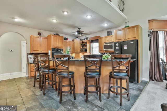 226 Long Island Dr, Whitesburg, GA 30185 - kitchen featuring black appliances, ceiling fan, dark countertops, a breakfast bar area, and a center island