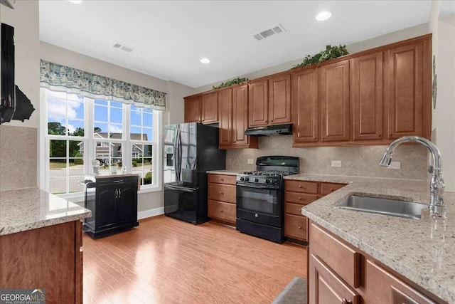 3554 Black Cherry Pt SW, Gainesville, GA 30504 - kitchen featuring black appliances, a sink, under cabinet range hood, light wood-style floors, and light stone counters