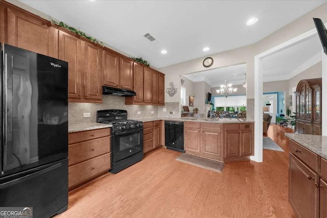 3554 Black Cherry Pt SW, Gainesville, GA 30504 - kitchen featuring black appliances, under cabinet range hood, light wood finished floors, a chandelier, and brown cabinetry