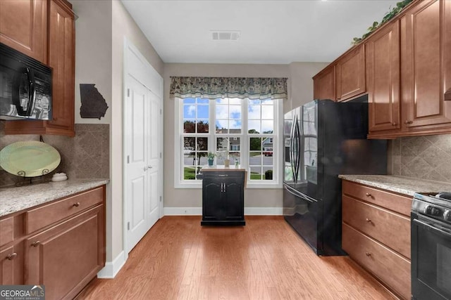3554 Black Cherry Pt SW, Gainesville, GA 30504 - kitchen with black appliances, light wood-style floors, brown cabinetry, and baseboards