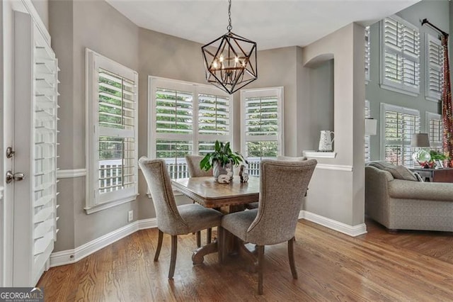 2073 Woodside Park Dr, Woodstock, GA 30188 - dining space with baseboards, a chandelier, wood finished floors, and arched walkways