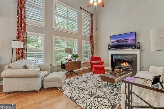 2073 Woodside Park Dr, Woodstock, GA 30188 - living room featuring wood finished floors, a tiled fireplace, a high ceiling, and a ceiling fan
