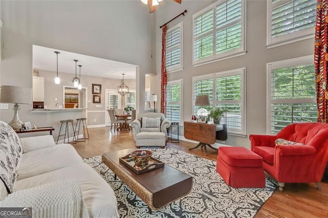 2073 Woodside Park Dr, Woodstock, GA 30188 - living room featuring a towering ceiling, wood finished floors, a chandelier, and baseboards