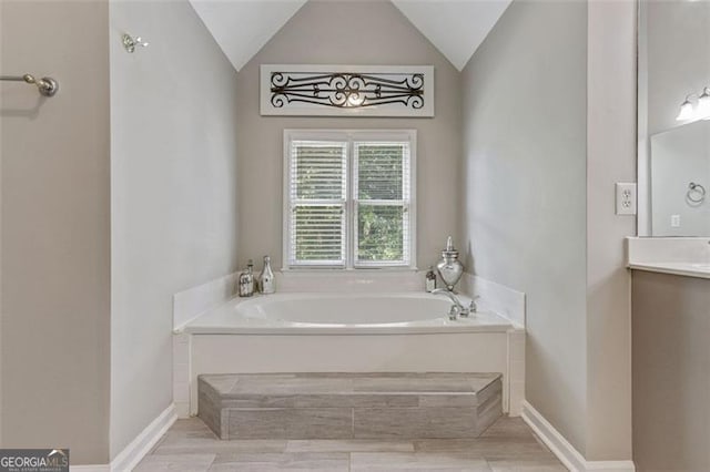2073 Woodside Park Dr, Woodstock, GA 30188 - bathroom with a bath, vanity, vaulted ceiling, baseboards, and wood finished floors