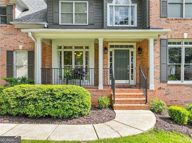 2073 Woodside Park Dr, Woodstock, GA 30188 - view of exterior entry with brick siding, a porch, and roof with shingles