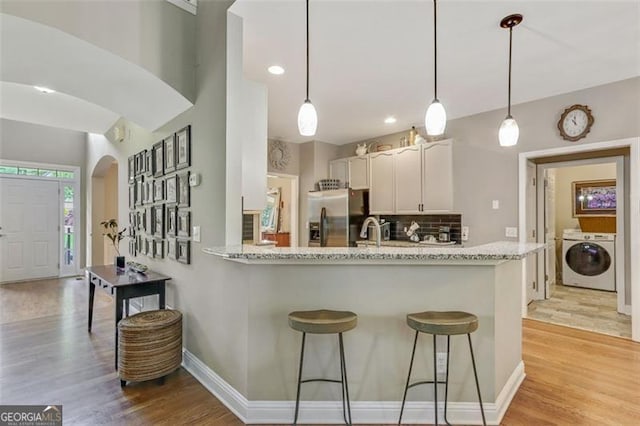 2073 Woodside Park Dr, Woodstock, GA 30188 - kitchen featuring stainless steel fridge, arched walkways, white cabinetry, light wood-type flooring, and decorative backsplash