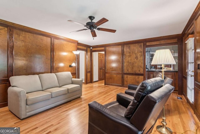 6165 Pin Oak Ln, Alpharetta, GA 30005 - living room with light wood-style flooring, ornamental molding, ceiling fan, wood walls, and a decorative wall