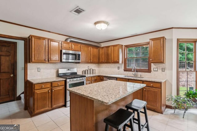 6165 Pin Oak Ln, Alpharetta, GA 30005 - kitchen featuring appliances with stainless steel finishes, a sink, brown cabinetry, tasteful backsplash, and a breakfast bar area
