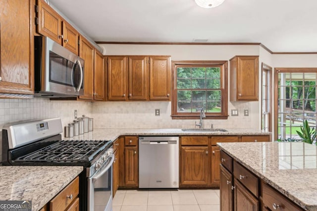 6165 Pin Oak Ln, Alpharetta, GA 30005 - kitchen featuring appliances with stainless steel finishes, a sink, light tile patterned floors, crown molding, and light stone countertops