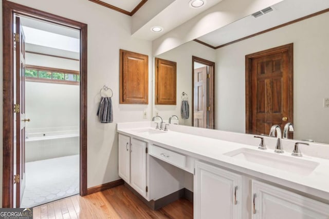 6165 Pin Oak Ln, Alpharetta, GA 30005 - bathroom featuring crown molding, double vanity, wood finished floors, tiled tub, and baseboards
