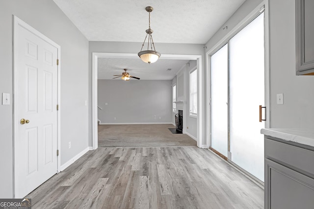 145 Silver Mine Trl, Austell, GA 30168 - unfurnished dining area featuring ceiling fan, a textured ceiling, light wood-type flooring, a fireplace with flush hearth, and baseboards