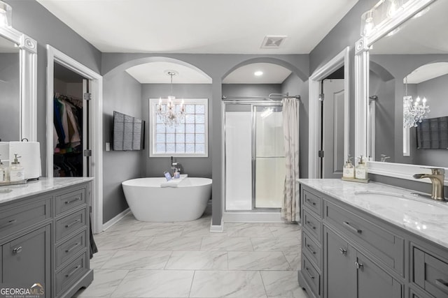 143 Monarch Way, Hiram, GA 30141 - bathroom featuring a chandelier, a shower stall, two vanities, marble look tiles, and a freestanding tub