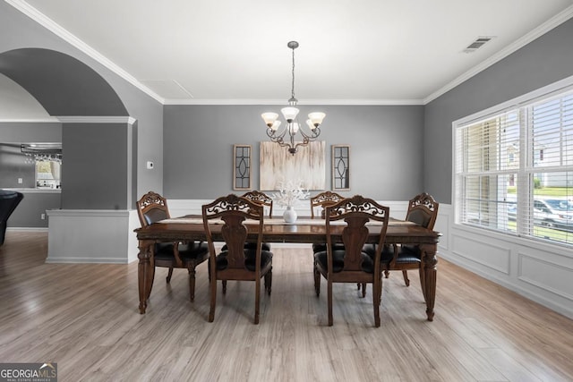 143 Monarch Way, Hiram, GA 30141 - dining area featuring a chandelier, light wood-style flooring, ornamental molding, arched walkways, and wainscoting