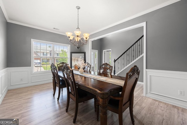 143 Monarch Way, Hiram, GA 30141 - dining space with a chandelier, a wainscoted wall, wood finished floors, crown molding, and stairs