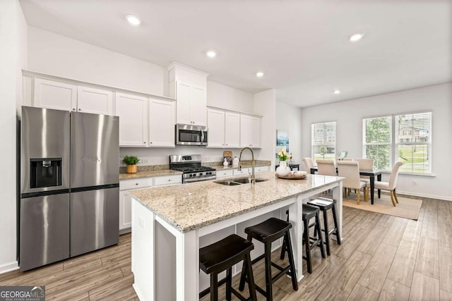 1172 Edwin Ln, Sugar Hill, GA 30518 - kitchen with stainless steel appliances, white cabinets, a center island with sink, light wood-style flooring, and recessed lighting