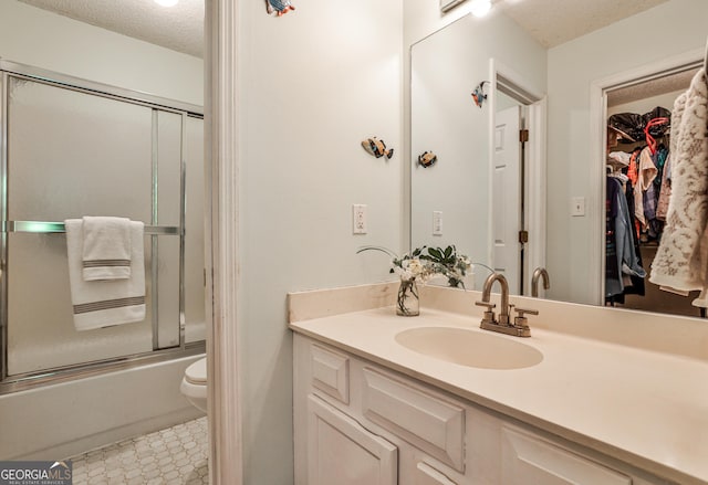 1750 Clairmont Rd Unit 35, Decatur, GA 30033 - full bathroom featuring a textured ceiling, vanity, toilet, bath / shower combo with glass door, and a walk in closet